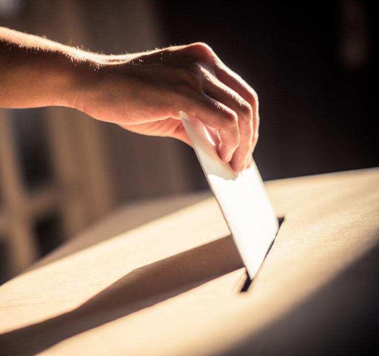 Hand dropping a ballot into an election box