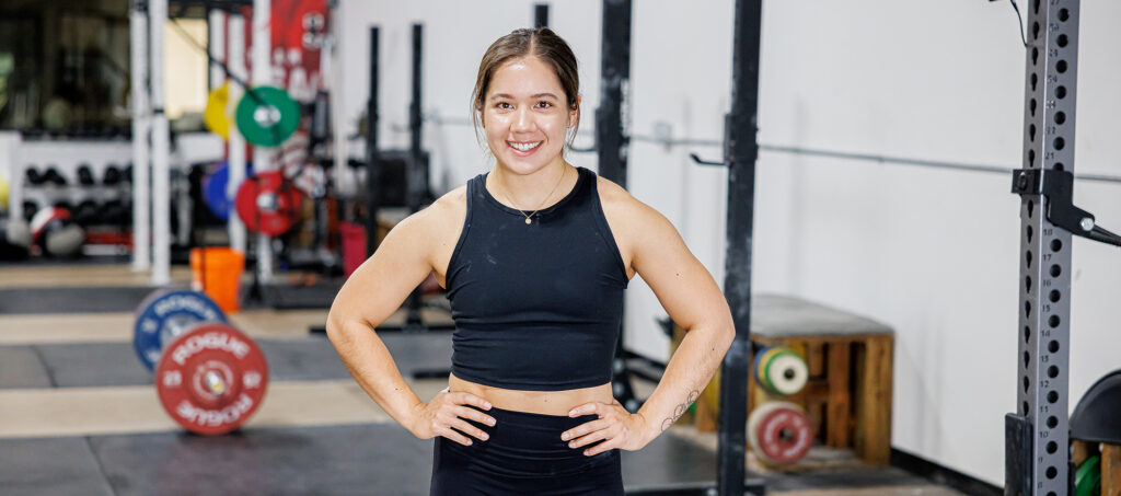 Woman stands smiling in a gym