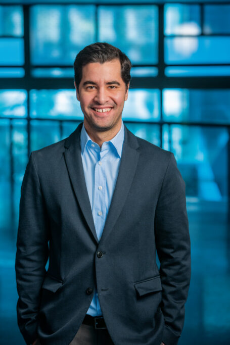 A male researcher in a blue suit smiles.