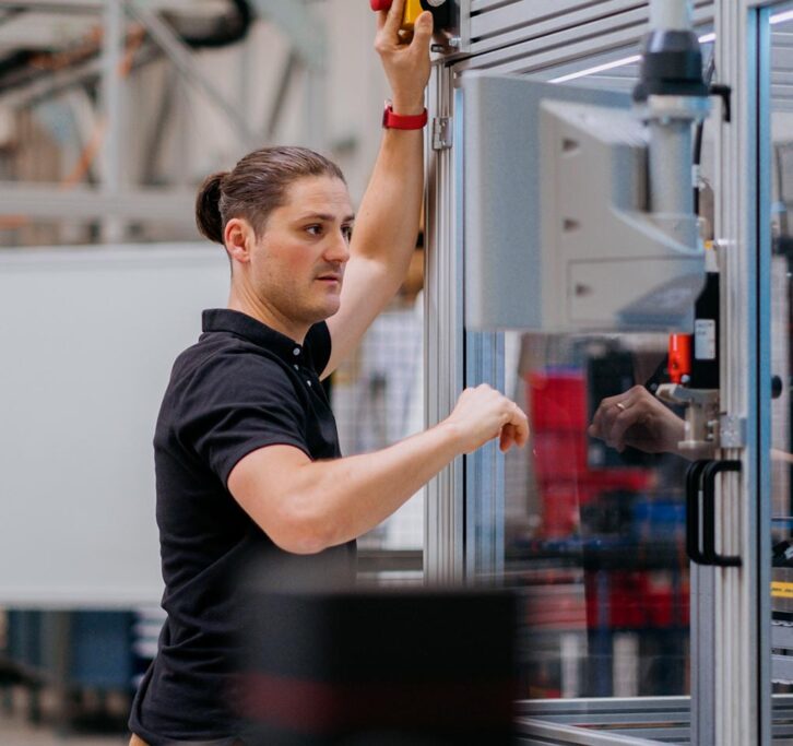 A man working on the exterior of a machine in a glass box.   