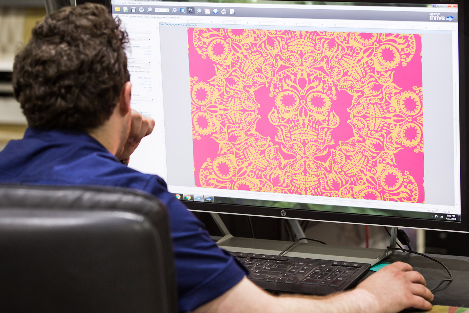 TPhoto of man working on computer displaying a colorful wallpaper pattern.
