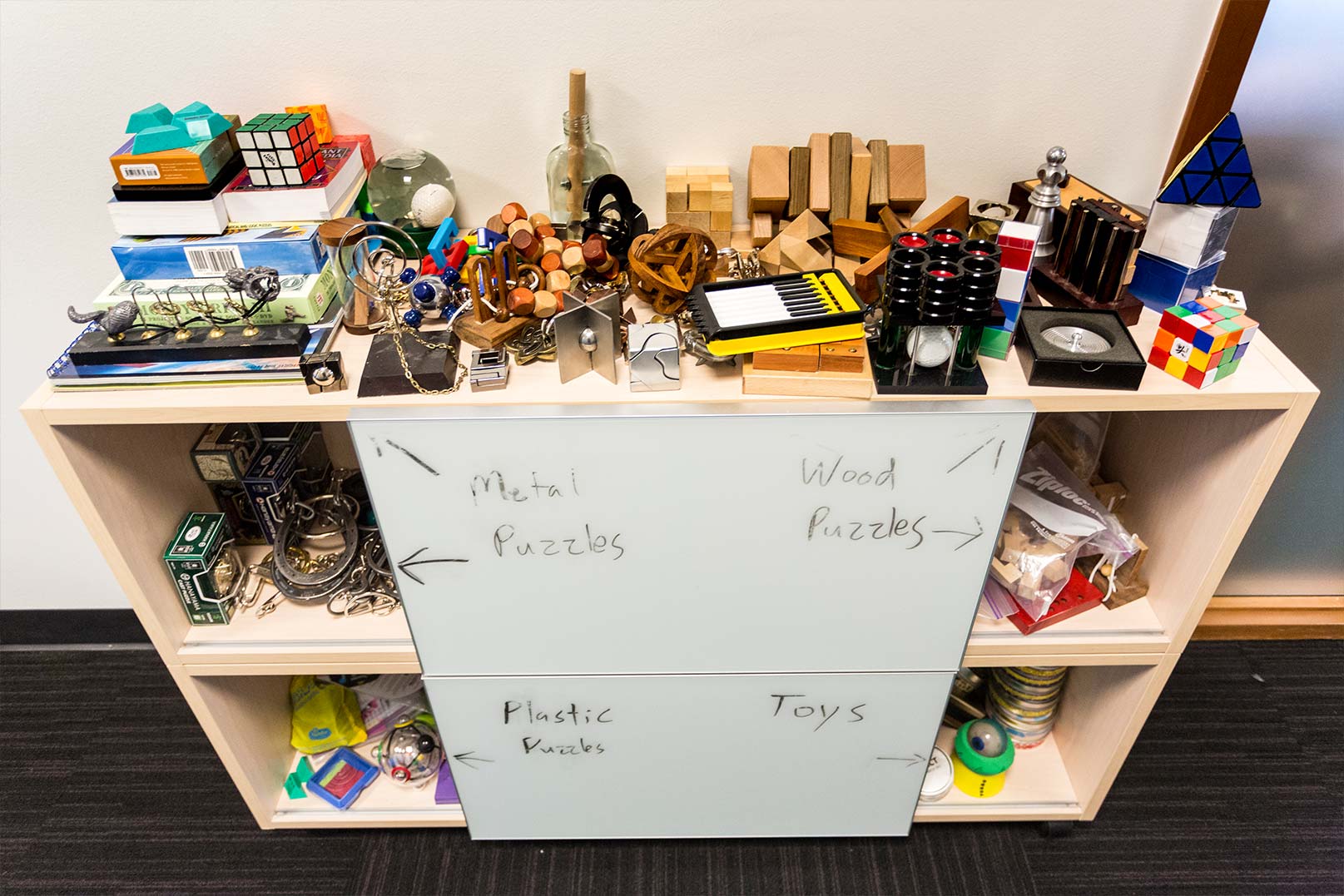 A shelf full of wooden puzzles sits outside Zach Johnson’s office door.
