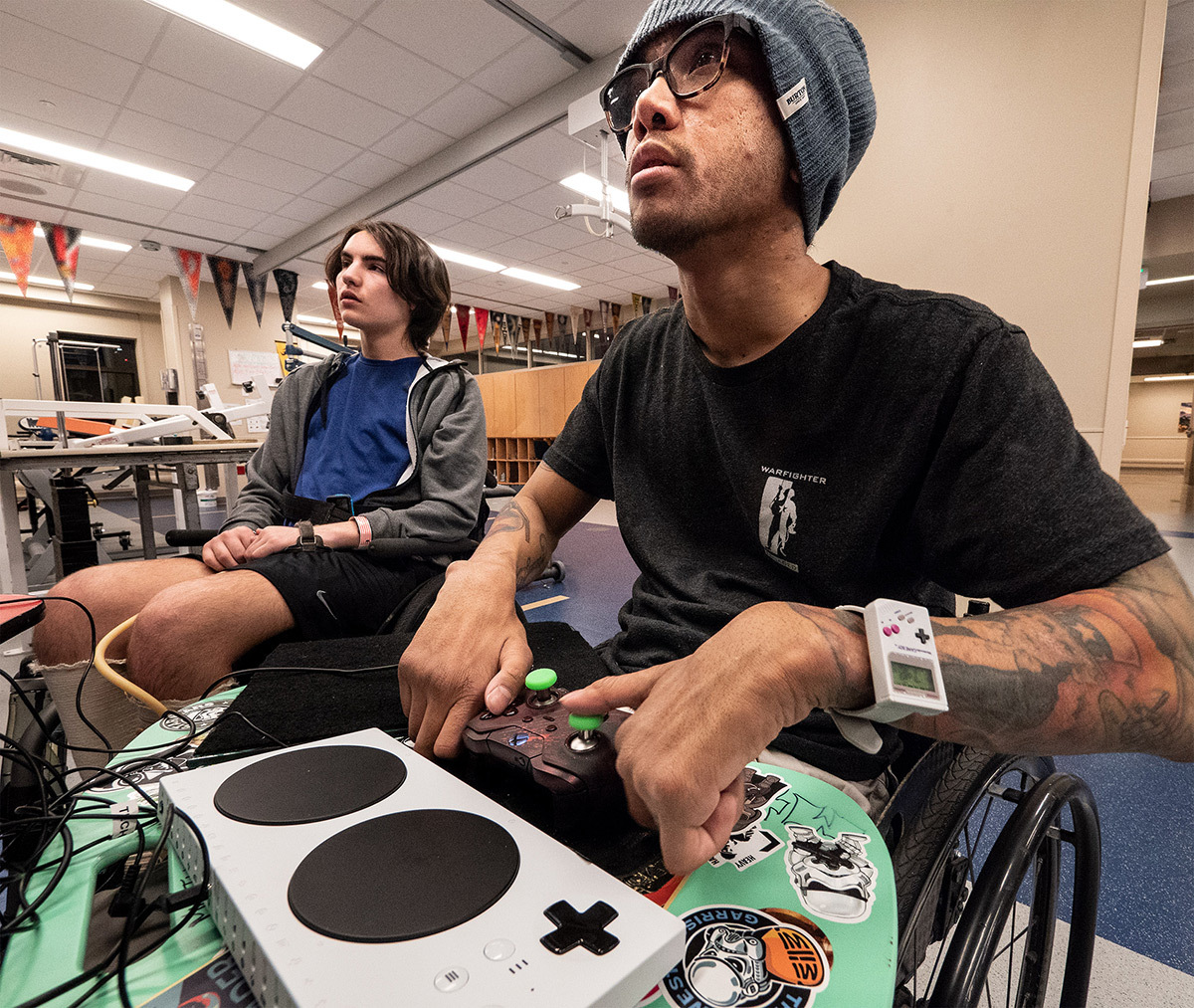 Patient Jonah Karpman, left, watches as Mike Luckett of Warfighter Engaged plays during Craig Hospital's gaming night.