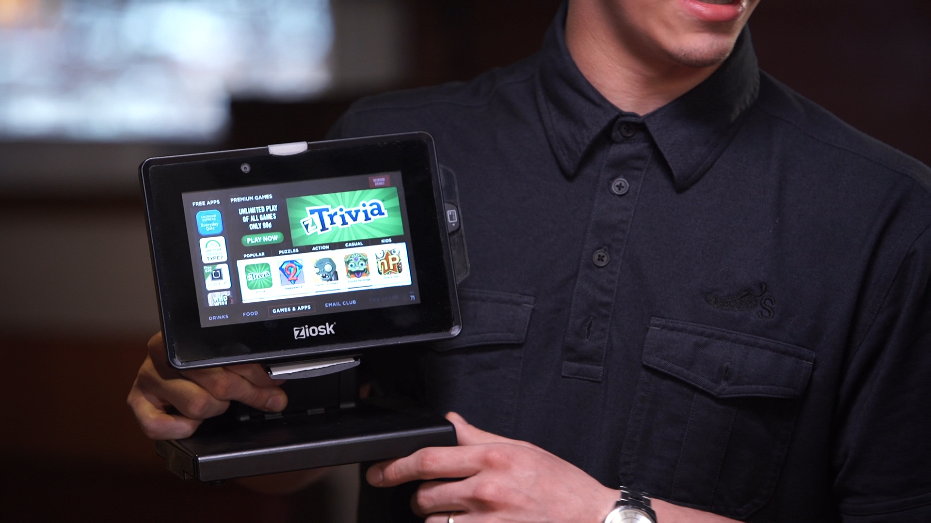 A Chili’s server holds up the Ziosk tablet to show some of the games available on it.