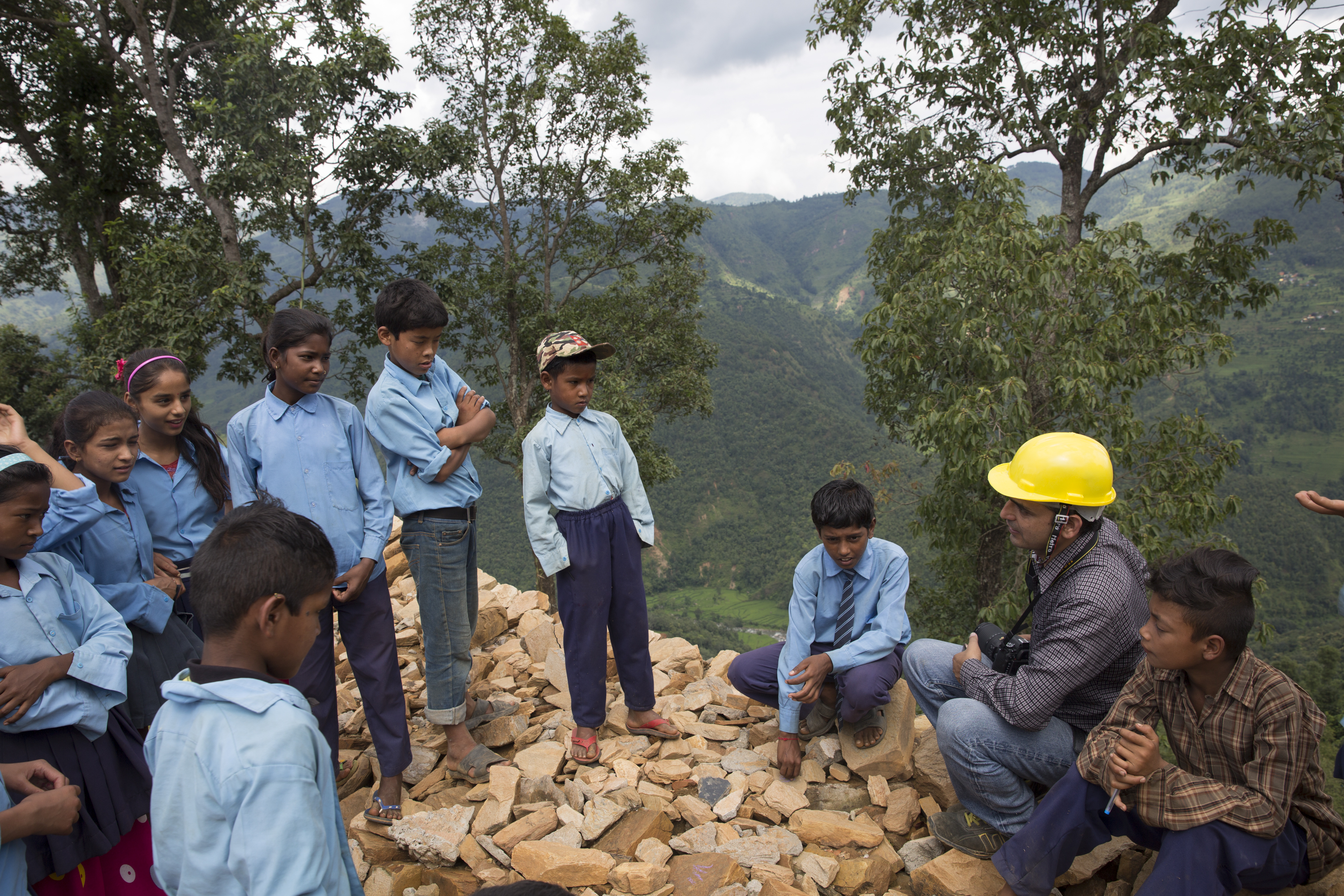 The UNDP’s Kamal Raj Sigdel talks to schoolchildren, standing atop a pile of rubble that was once their school.
