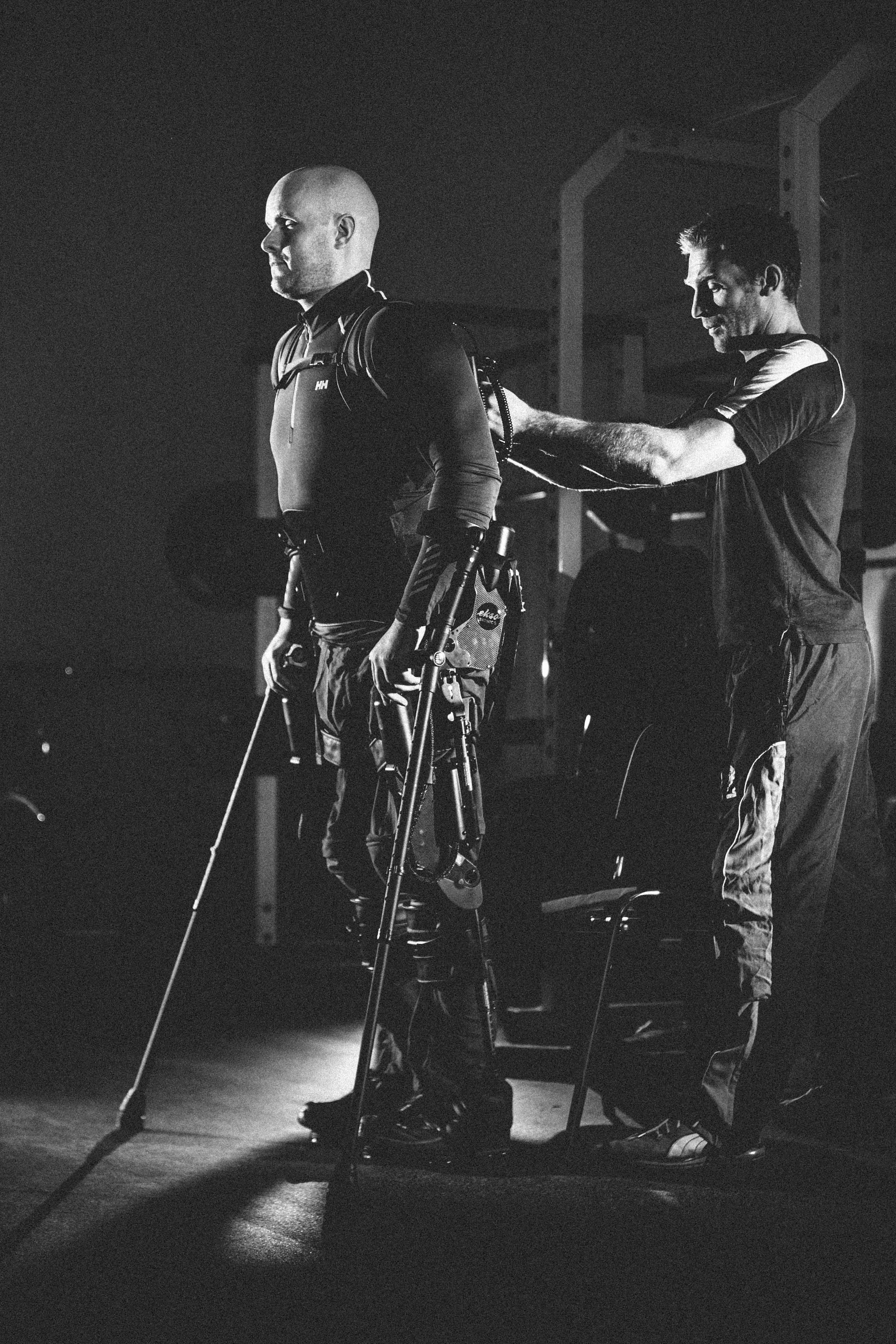 ALL IMAGES COPYRIGHT MARK POLLOCK TRUST. An assistant helps Mark Pollock stand while he is in his Ekso Bionics robotic exoskeleton.