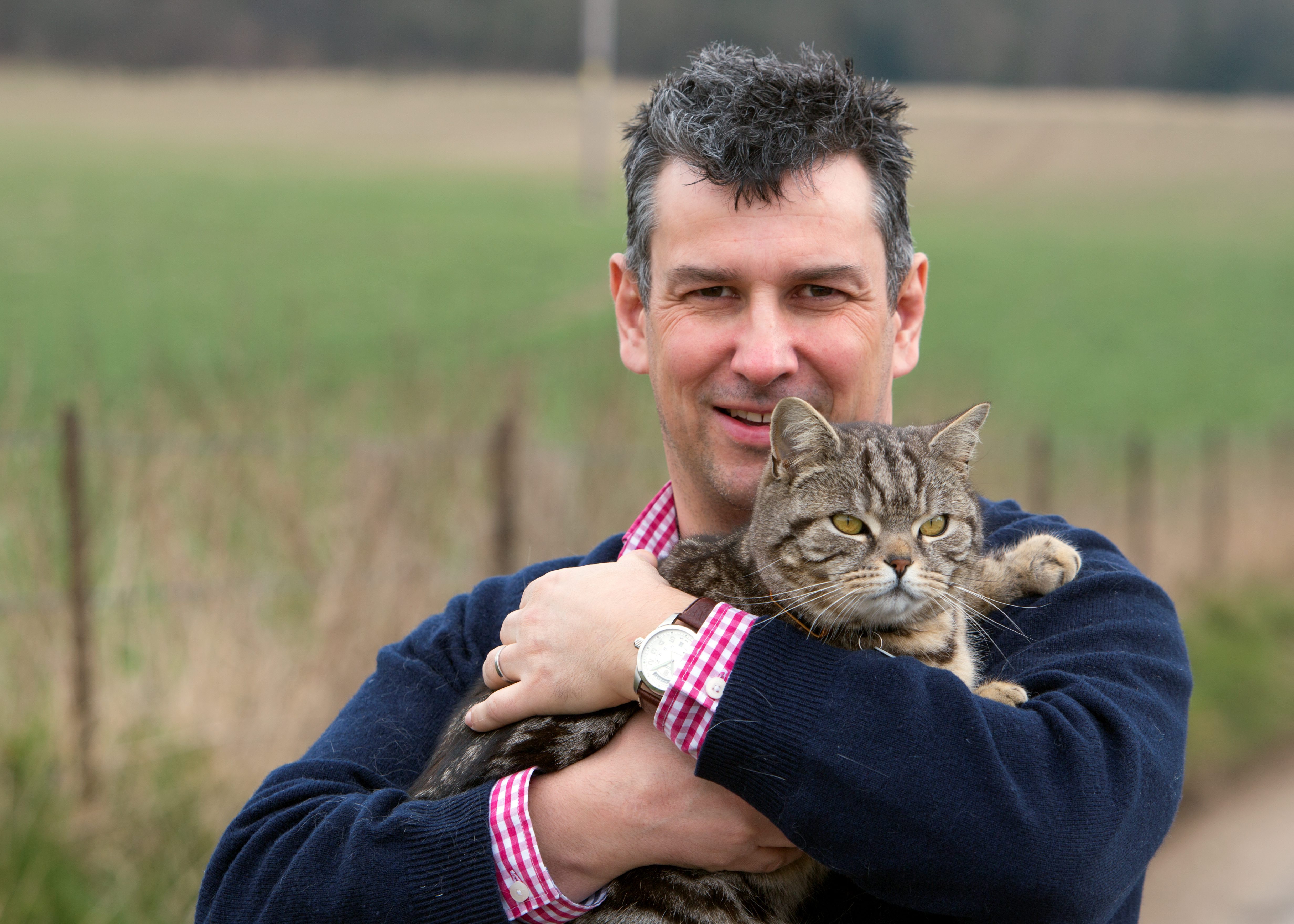 Dave Evans, 42, marketing manager, Marlborough, with 'Yollo' the cat, wearing a G-Paws GPS tracker. 27 March 2013 See swns story SWCATNAV. A pet owner has developed a new tracking device for animals dubbed 'Cat Nav' - which tracks their every move and maps it on Google. Dad-of-two Dave Evans from Marlborough, Wilts came up with the idea because his own silver tabby Yollo was mysteriously disappearing and putting on weight each day. He developed an ultra-light GPS which fixes to the pet's collar and records where it has been. When the animal returns home the information is downloaded via a USB cable direct to a website which reveals its secret life on Google Earth satellite images. Dave, 41, says the weatherproof tracker, weighing just 15g, will cost £50 and can be used for cats and dogs.