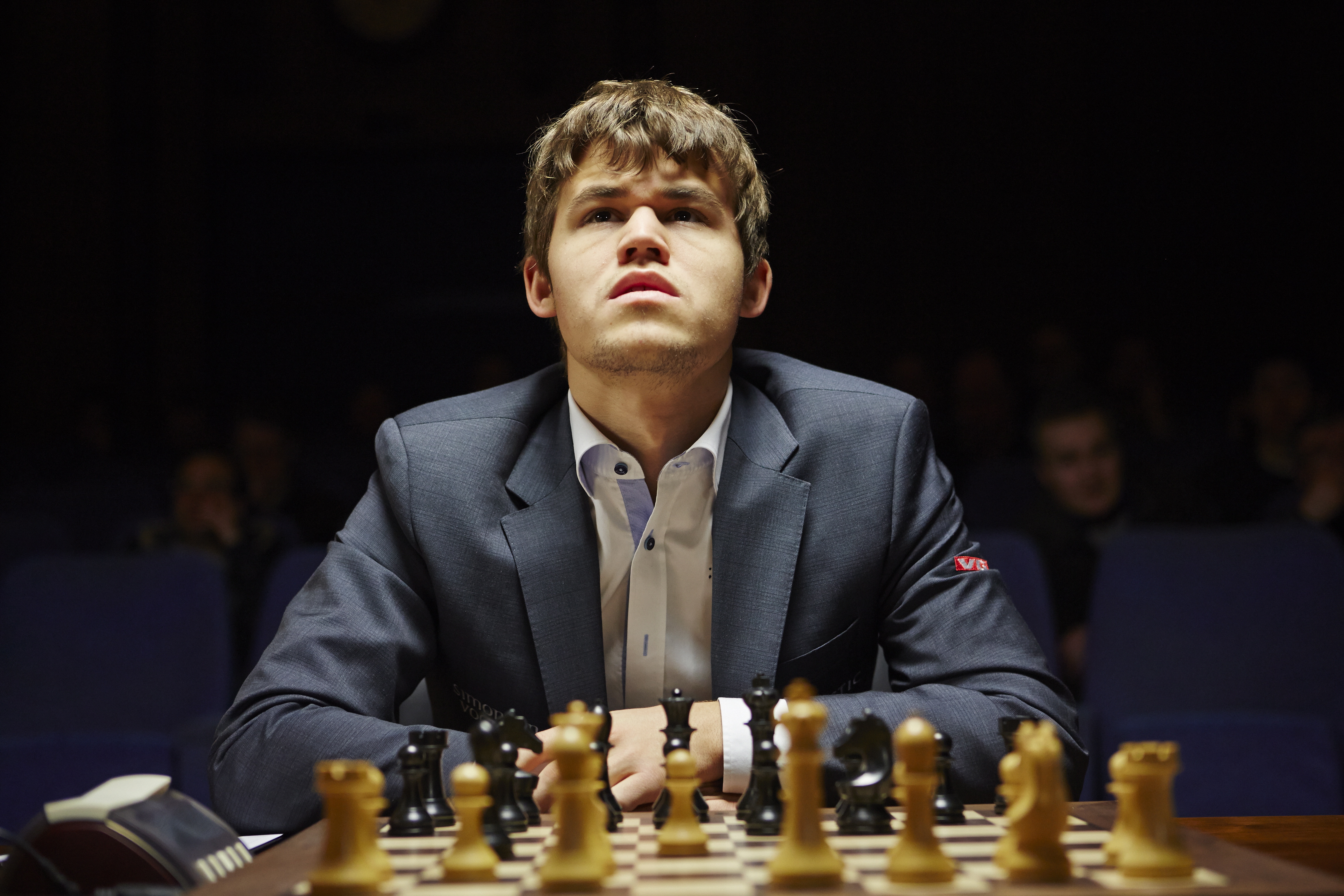 Magnus Carlsen sitting before chess board.