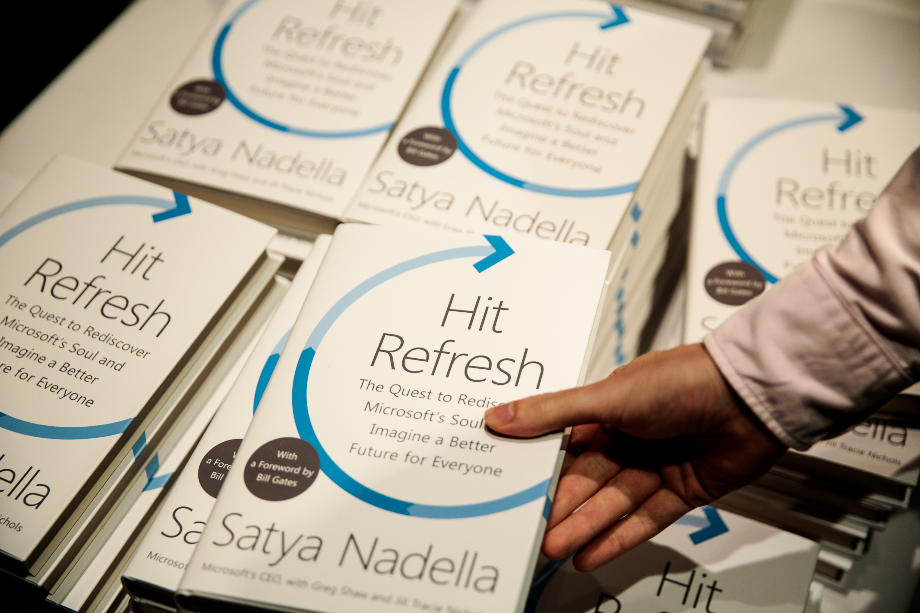 A person takes a copy of Hit Refresh, by Satya Nadella, from a table