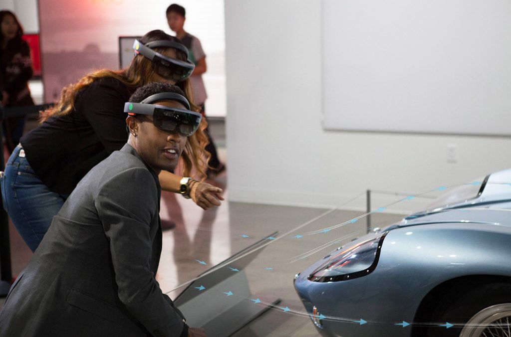 Man and woman wearing HoloLens headsets in front of an exhibit at Petersen Automotive Museum