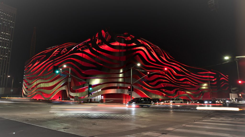 Exterior photo of the Petersen Automotive Museum lit up at night. 