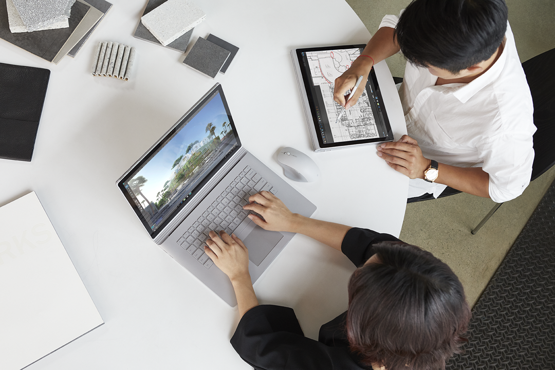 Two people working at a desk on Surface laptops