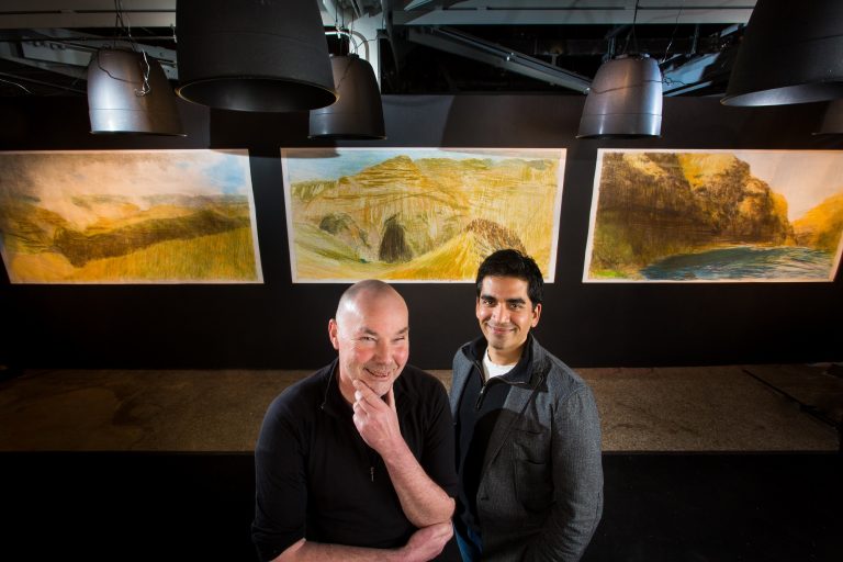 Keith Salmon and Neel Joshi stand in front of three drawings of Hells Canyon