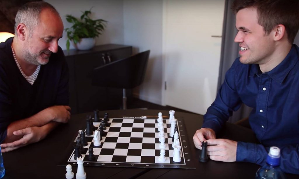 World chess champion Magnus Carlsen, right, with his manager Espen Agdestein, both seated near a chess set.