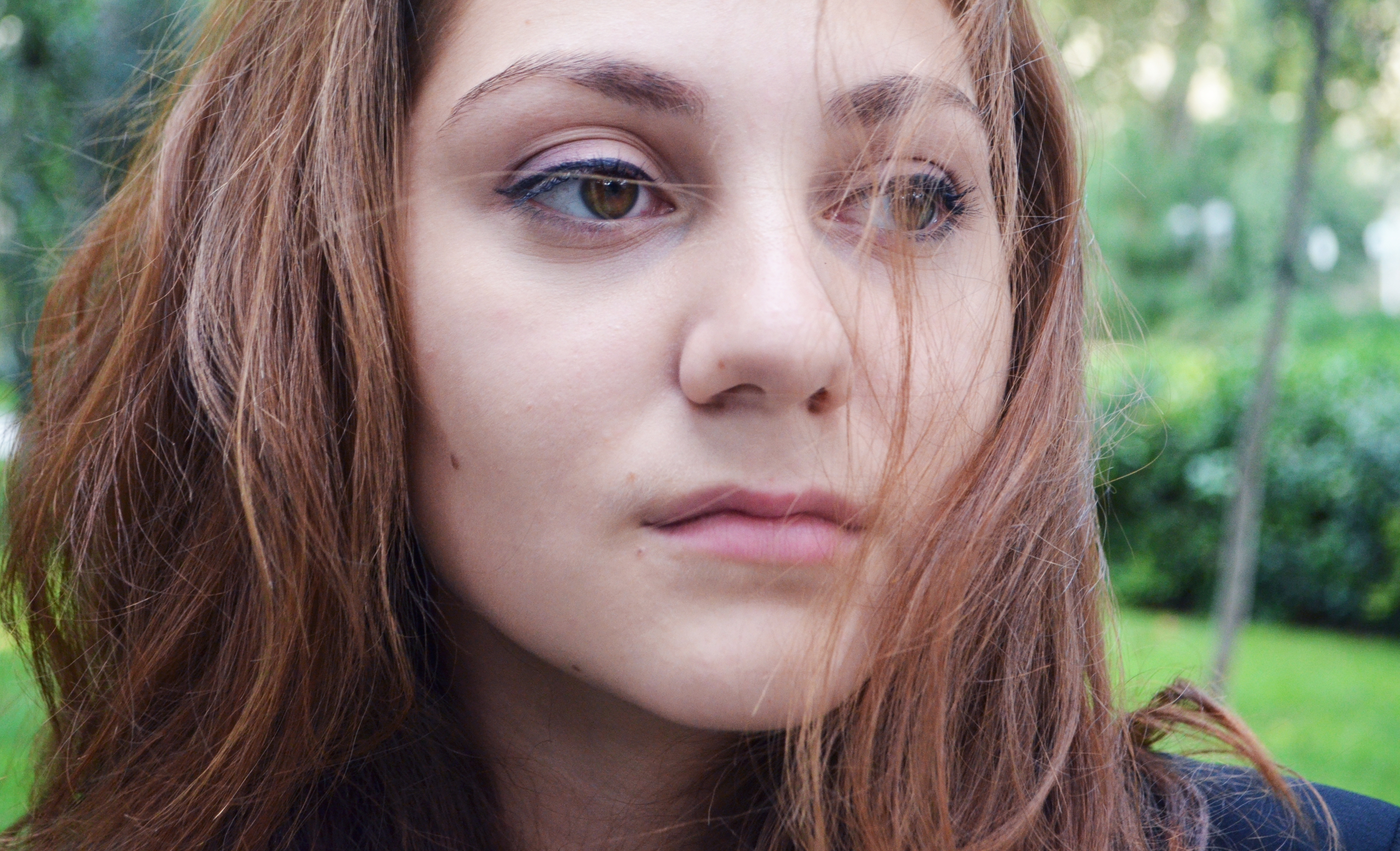 Close up portrait of a woman's face, taken outside in a park