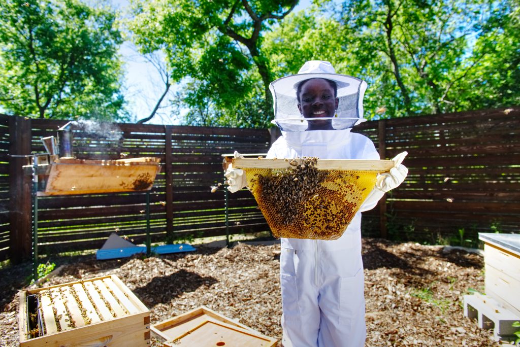 Photo of girl beekeeper holding net of bees