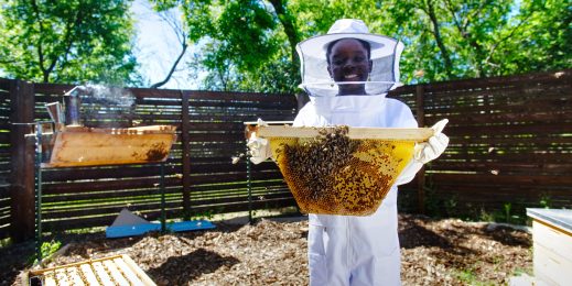 Photo of girl beekeeper holding net of bees