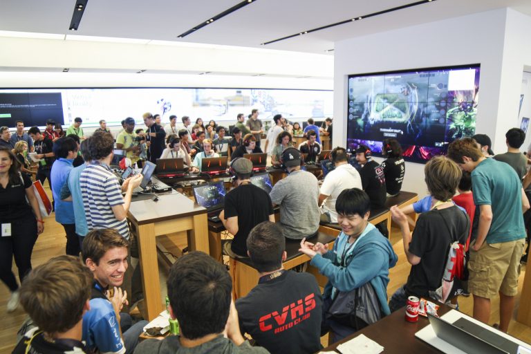 A full room of gamers gather around tables