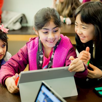 three little girls gather around a laptop