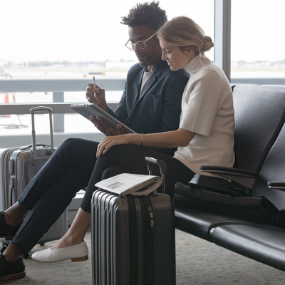 A man and a woman sit in an airport using a Surface tablet
