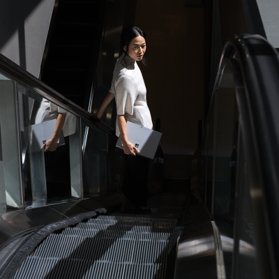 A woman holds a Surface tablet as she rides an escalator