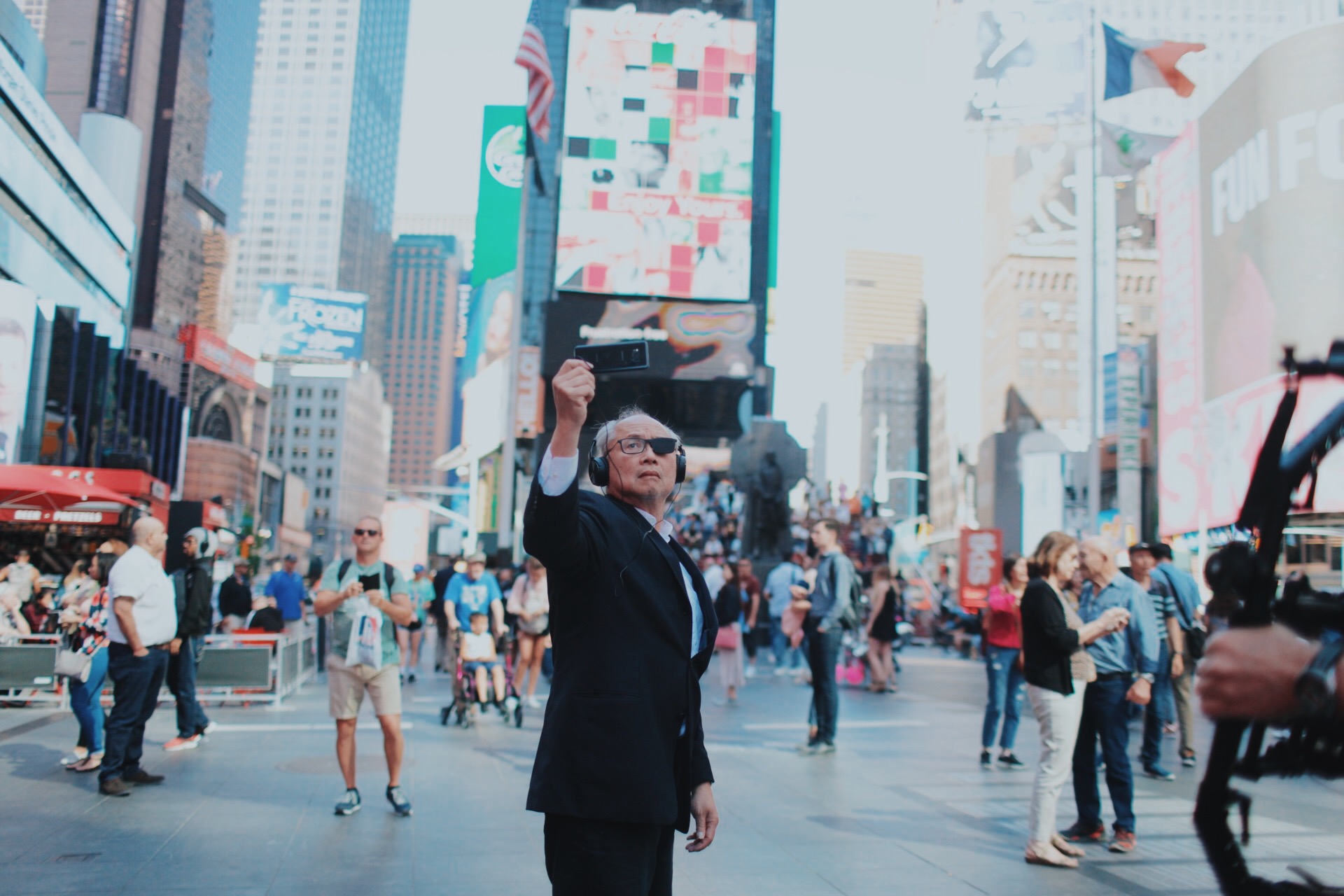 Artist Mel Chin holds a cellphone in front of him at Times Square