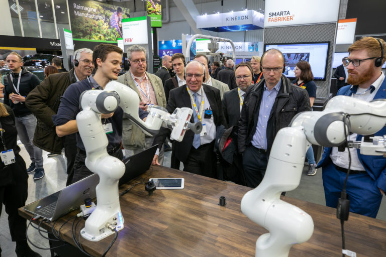A booth tour group enjoys a robotics demo at Hannover Messe 2019