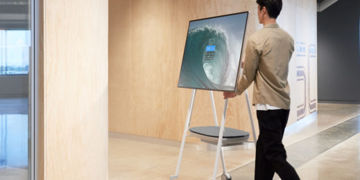 Man wheeling a Surface Hub 2S into a meeting room