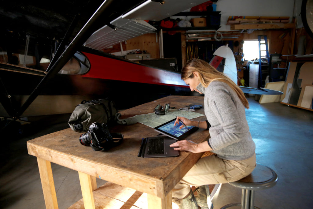 Jody MacDonald inside next to a plane working on a table with her HP device and digital pen