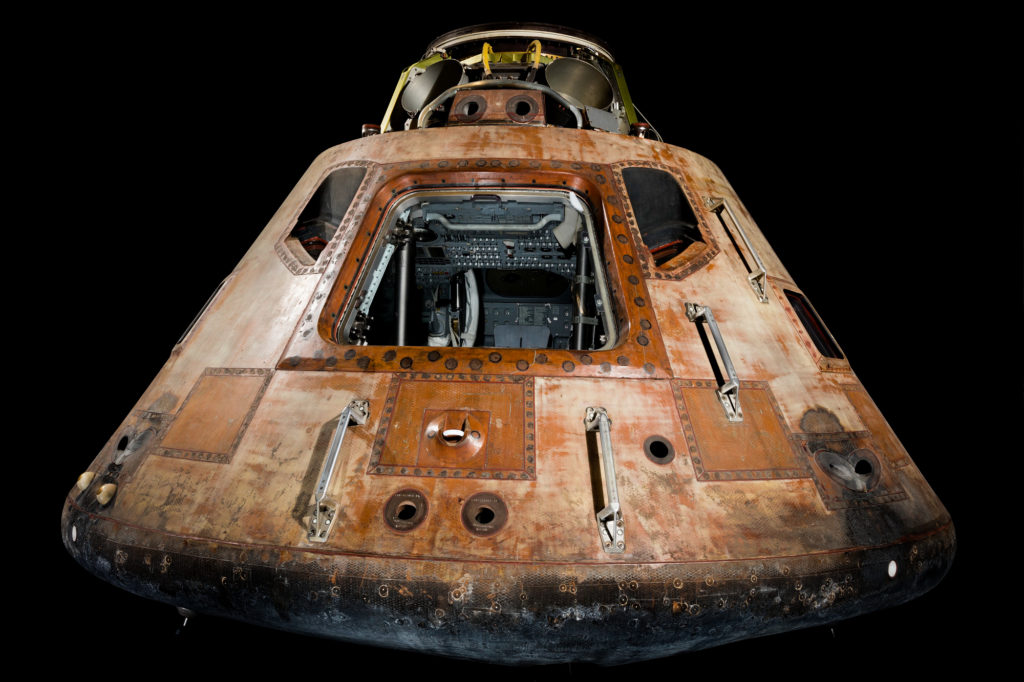 Empty Columbia command module photographed against black background