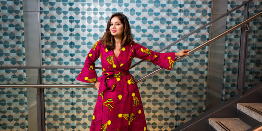 Portrait of Dona Sarkar in a colorful dress in front of a wall with a bold pattern