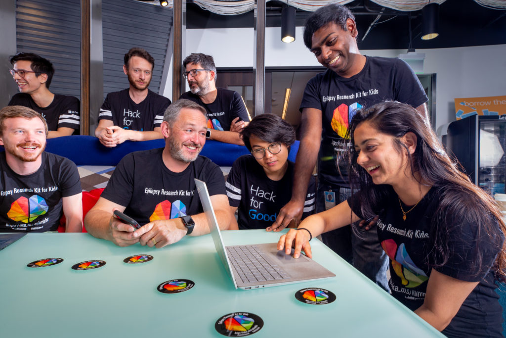 Redmond-based member of the MirrorHR team sitting at a table in matching team t-shirts working and smiling in front of a laptop