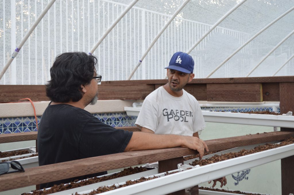 Dennis McClung talks with a man inside a greenhouse.