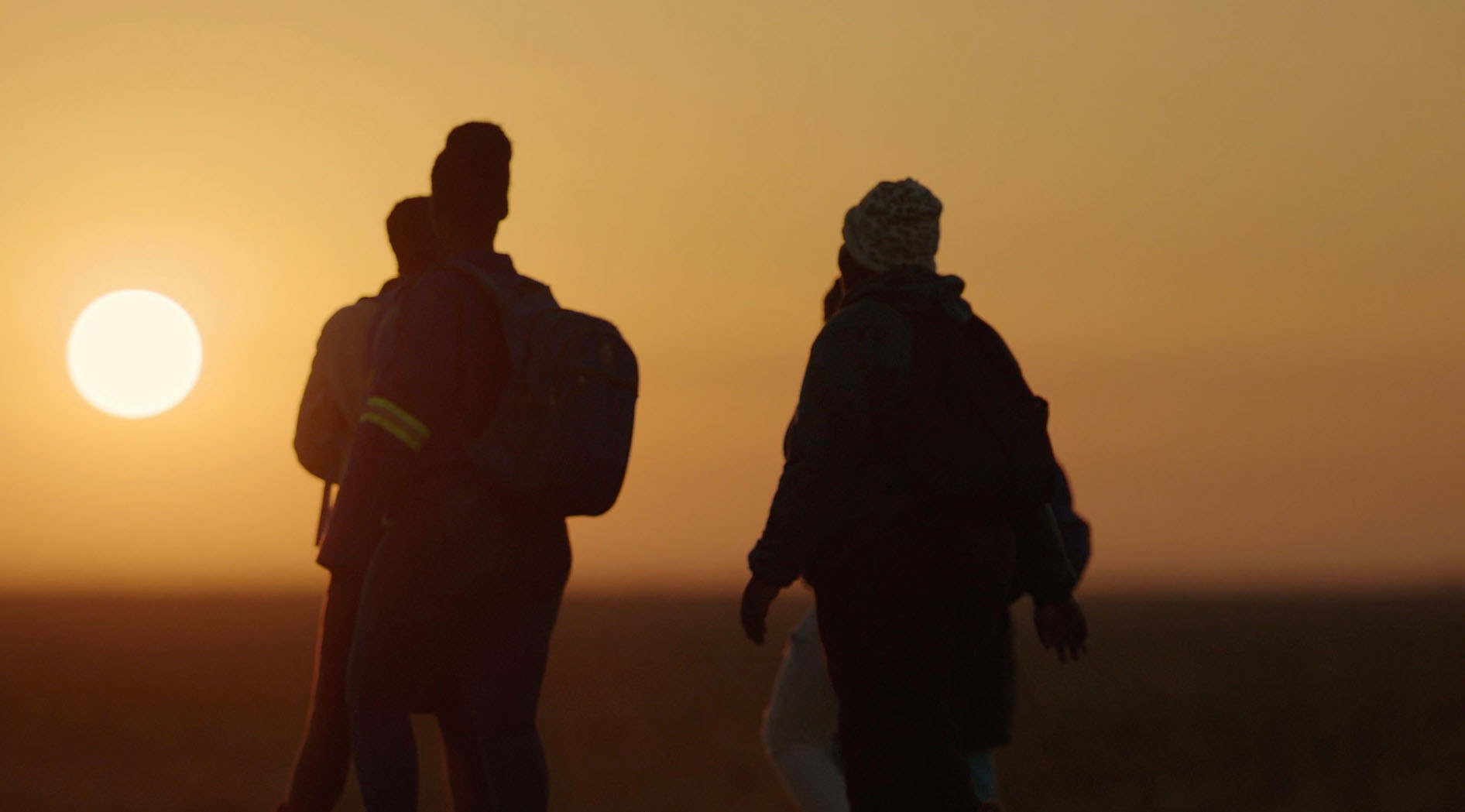 Two people walk toward a setting sun in Africa