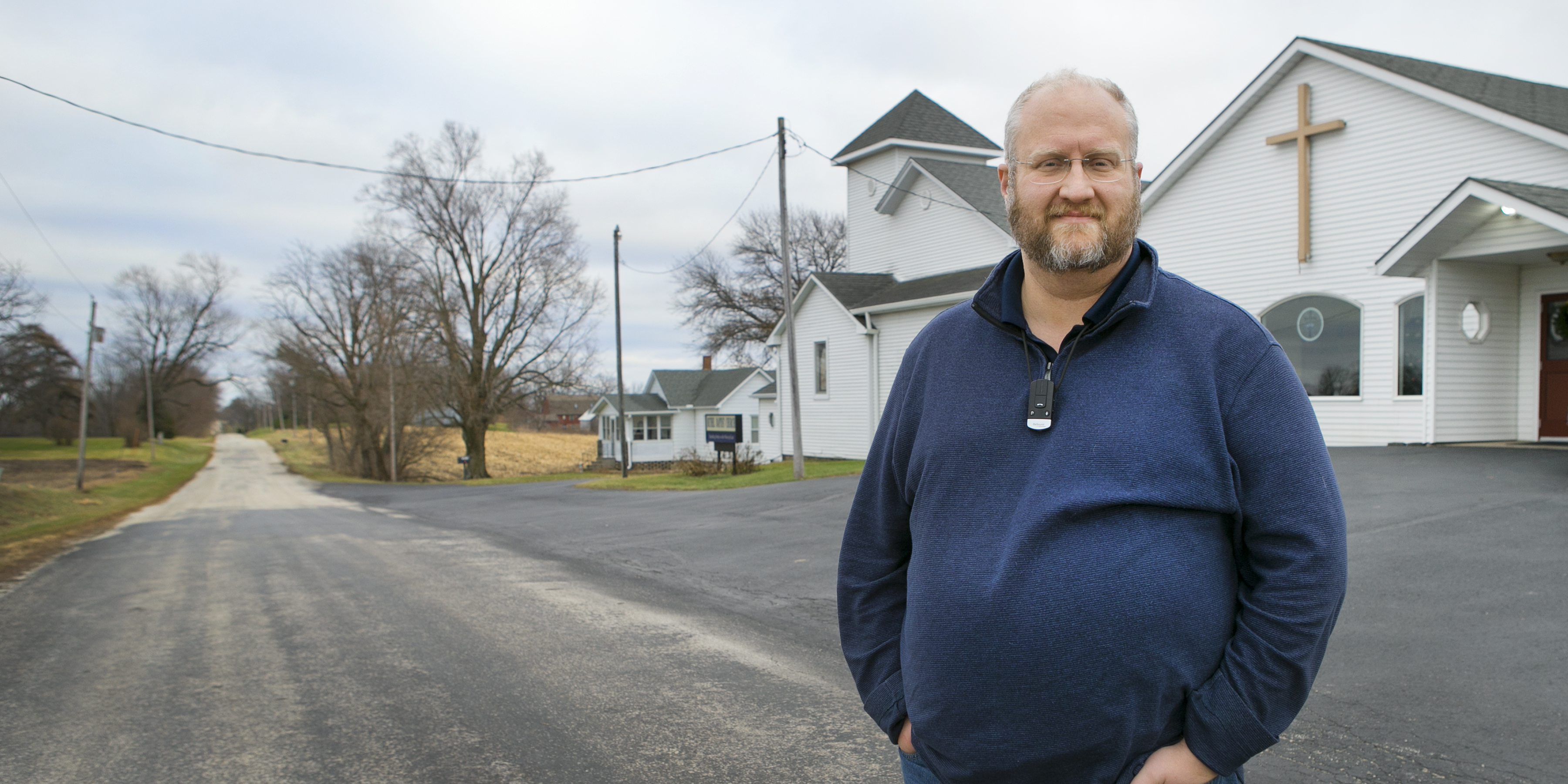Photo of Lee Williams, minister of Bethel Baptist Church in Port Byron, Illinois, standing in the road outside his church.