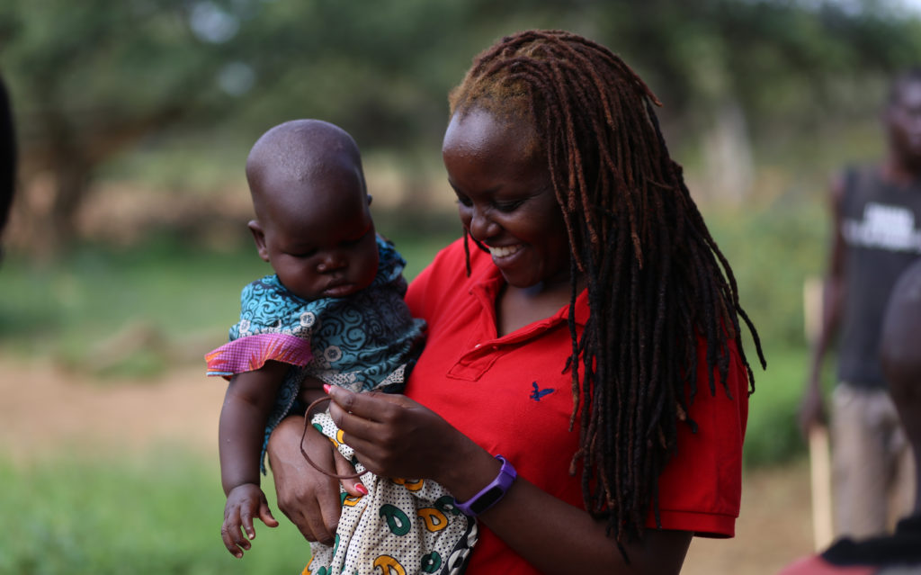 Reporter Verah Okeyo holds a baby on her visit to West Pokot County in Kenya