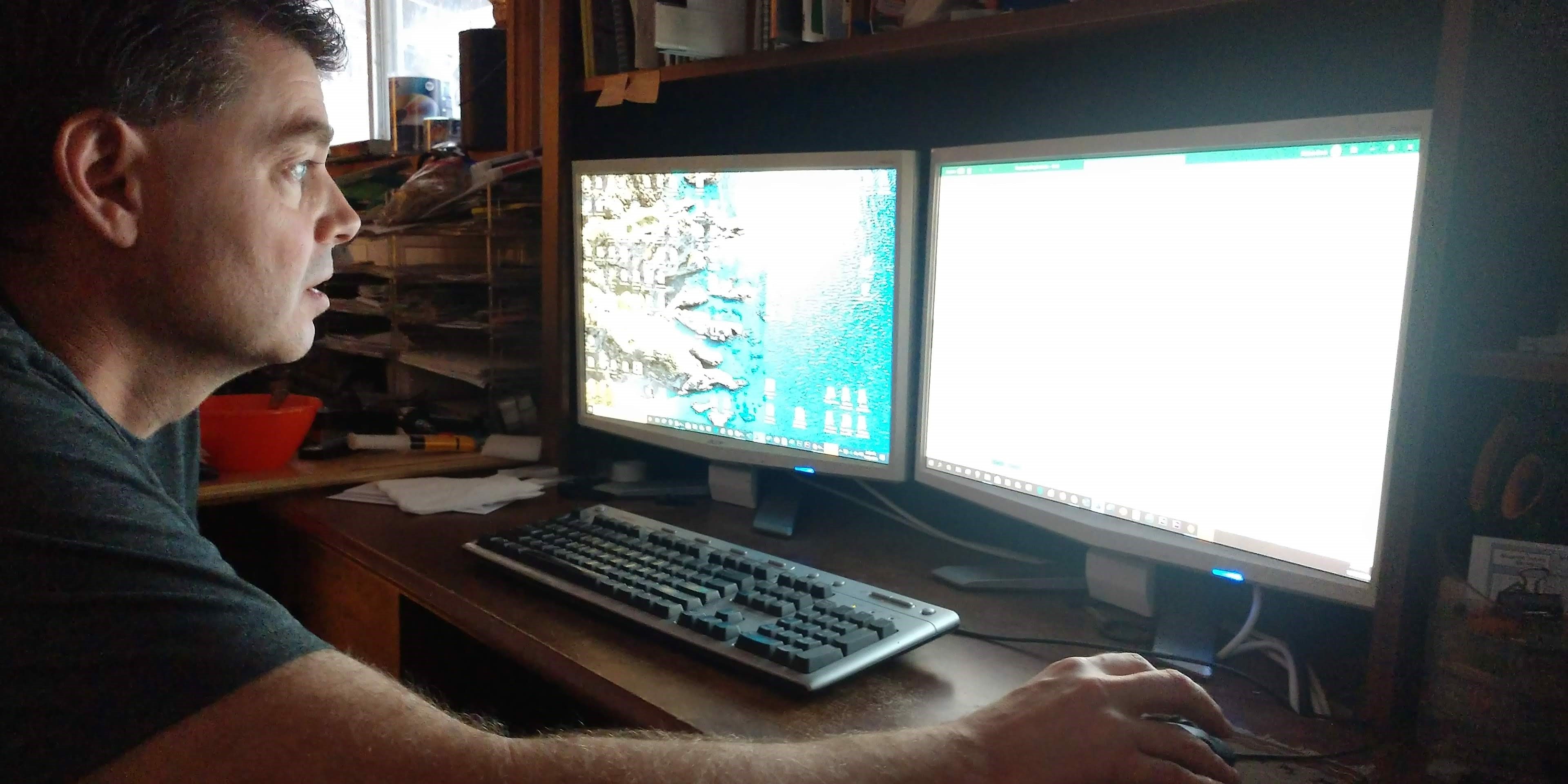 Photo of Nathan Davis sitting in front of two computer monitors.