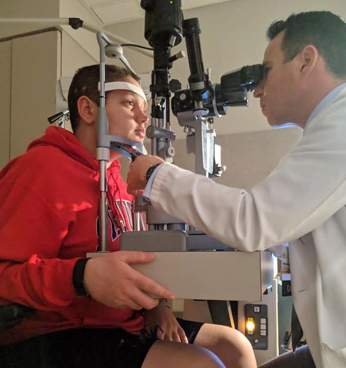 Photo of teenager Xander Carlson being examined by a doctor during treatment for a brain tumor.