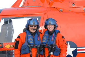 A man and a woman stand in front of a helicopter.