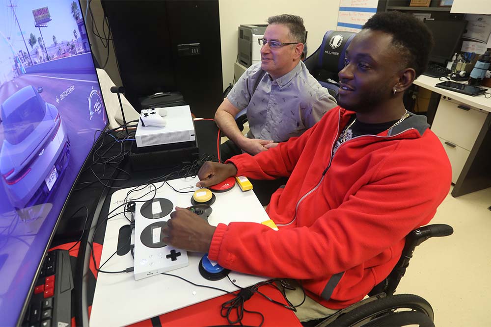 A Veterans Affairs recreation therapist watches a U.S. Army veteran play a video game