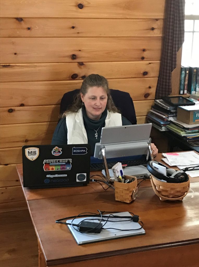 A woman works on a laptop computer inside her wood-paneled home
