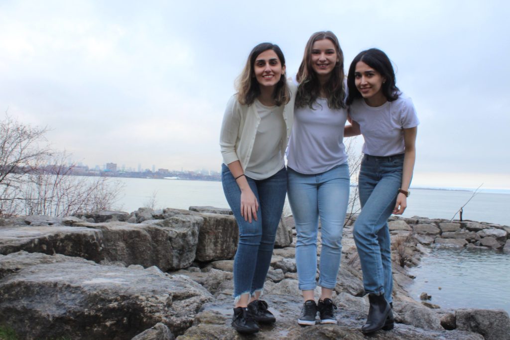 three young women pose near water