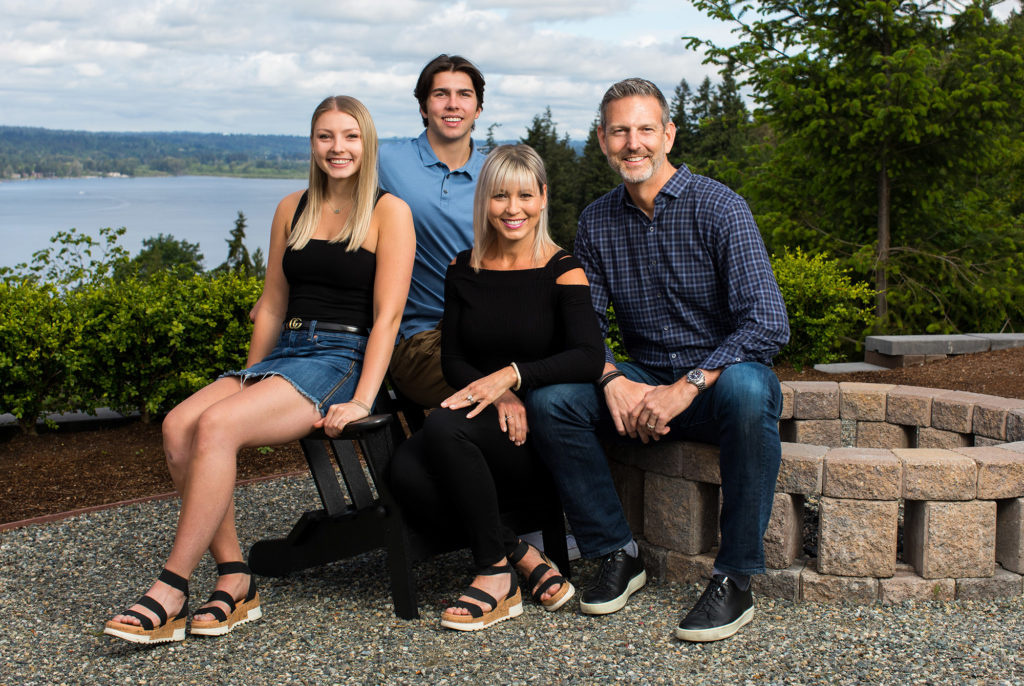 Outdoor smiling family portrait with view of lake and sky in background