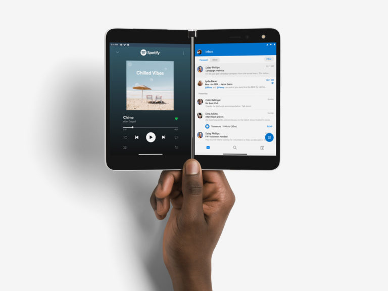 Hand holding Surface Duo displaying Spotify and Outlook