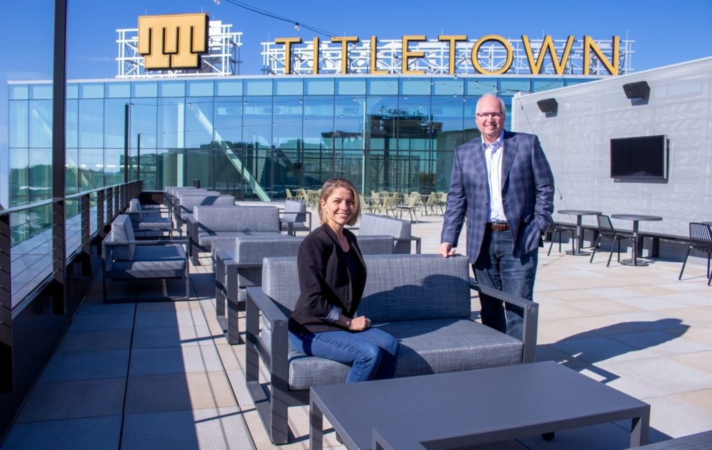 Woman and man in outdoor portrait under sign that says Titletown