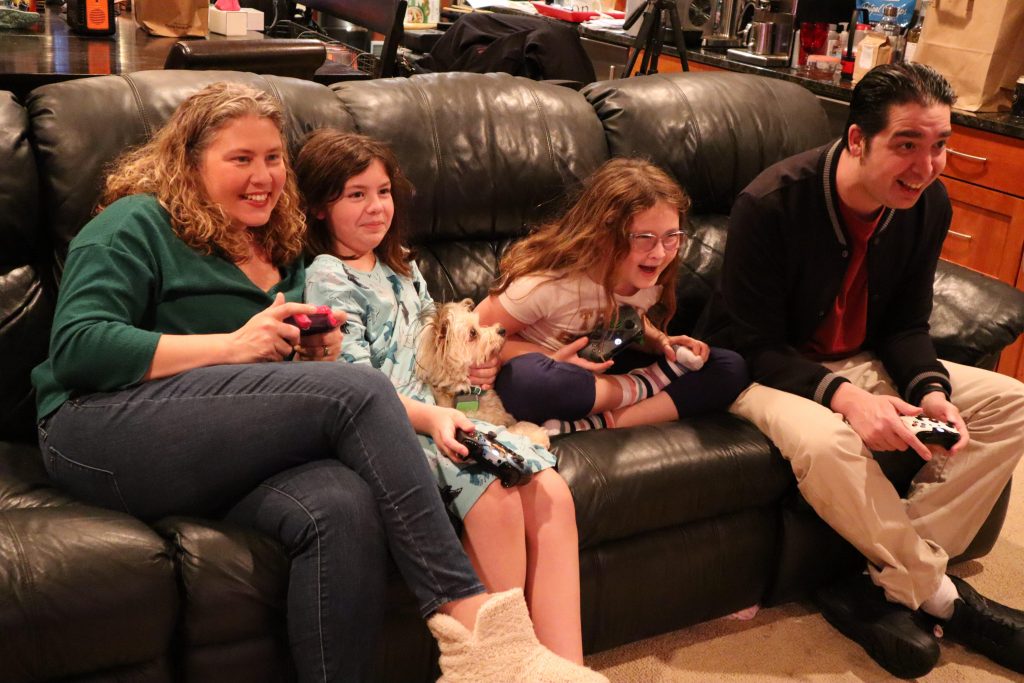 Family of four playing video games together on their couch