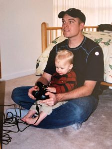 Dave McCarthy playing video games with his toddler son on his lap