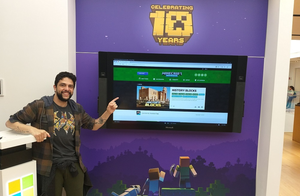 Male teacher stands in front of a screen that says History Blocks and Minecraft: Education Edition