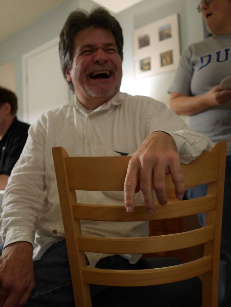 Paul Martin, in a chair, facing the back of it, laughing