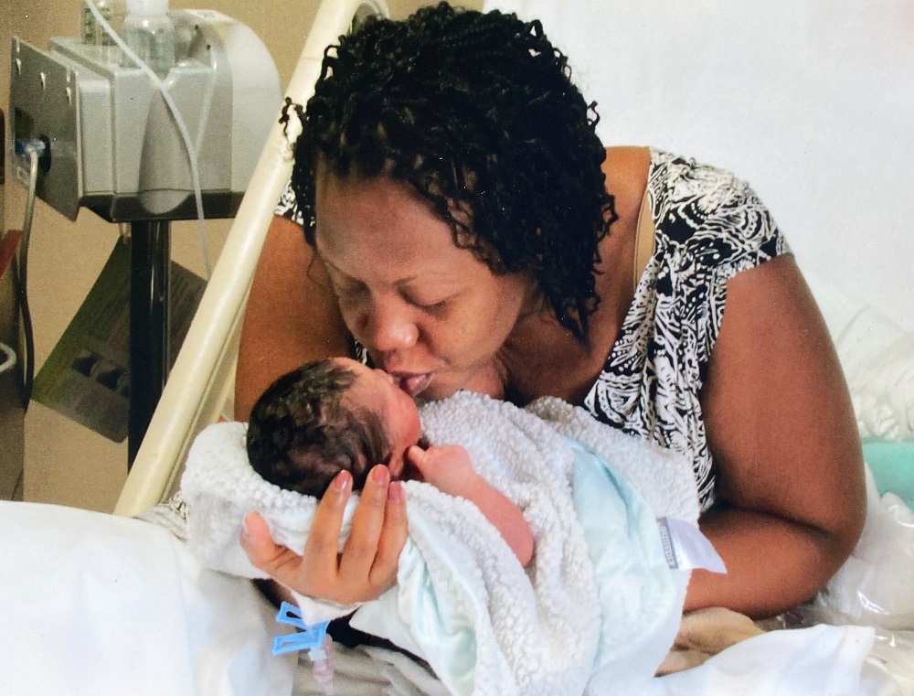 A mother kisses her newborn daughter in the hospital